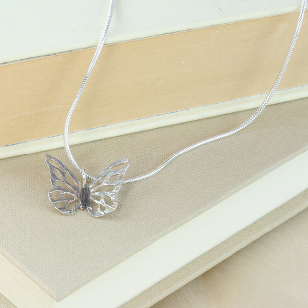Silver hand sawn butterfly. It has a striped texture and a shiny silver finish. Apart from the body which has been oxidised slightly to give it a darker look. The nexklace is made of snake chain and closes with a lobster clasp.