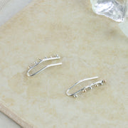 Silver ear climbers made from silver wire that hooks through the ear. Three silver and three 9ct gold balls are attached to the front of the earrings. They have a shiny mirror finish. They hug the ear and are adjustable by pinching them slightly.