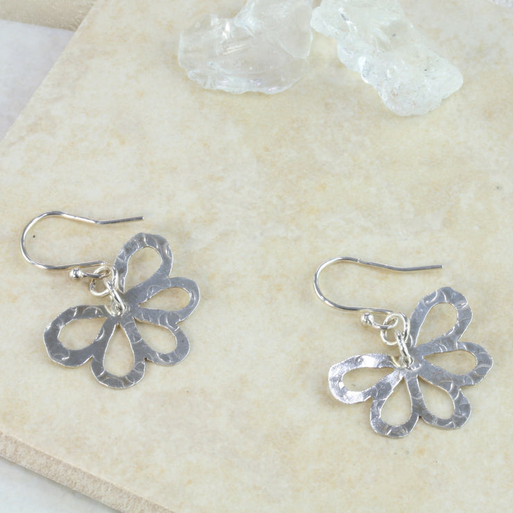 Silver earrings with a flower shape with five rounded petals. They have a hammered texture and mirror finish.