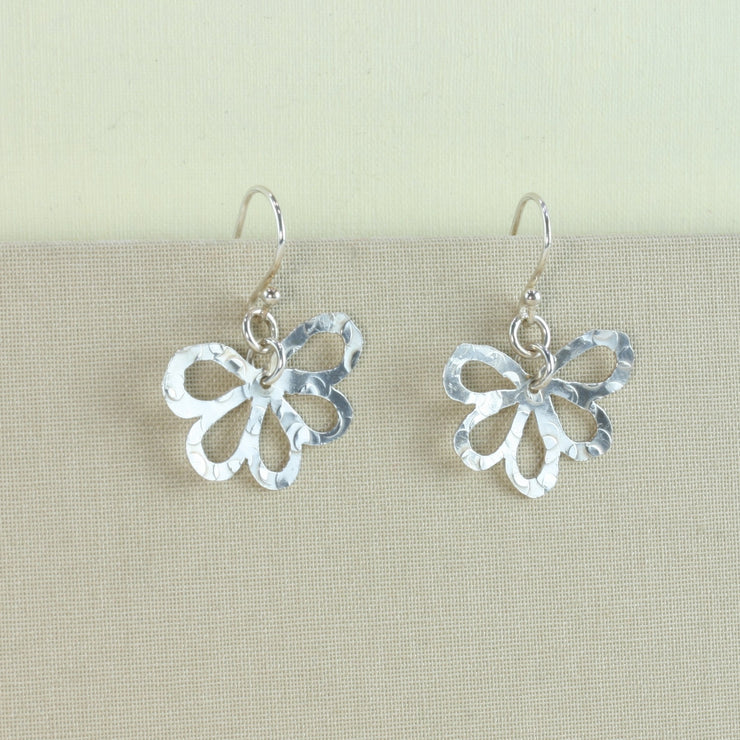 Silver earrings with a flower shape with five rounded petals. They have a hammered texture and mirror finish.