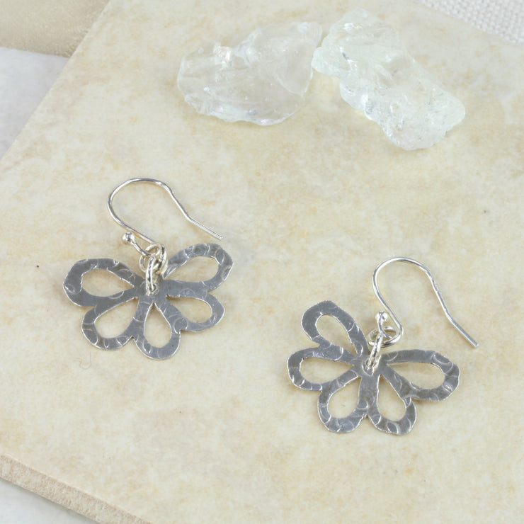 Silver earrings with a flower shape with five rounded petals. They have a hammered texture and mirror finish.