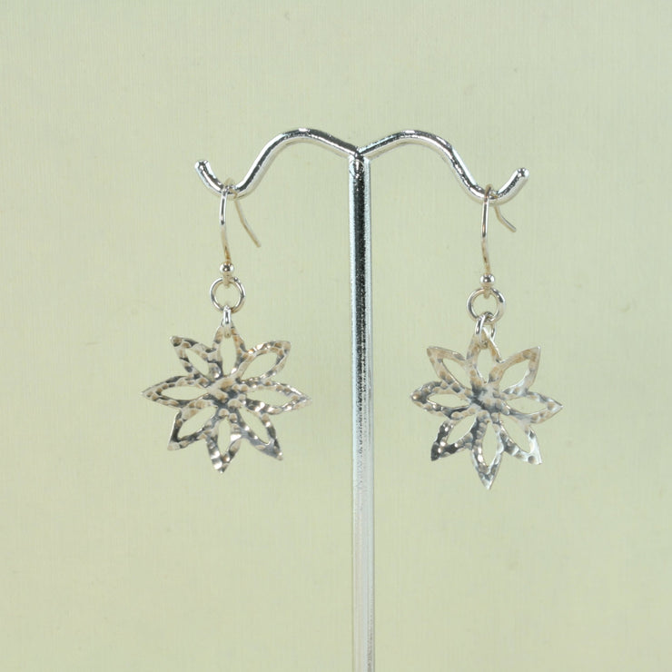 Silver earrings with a flower shape with sharp pointed petals. They have a hammered texture and mirror finish.