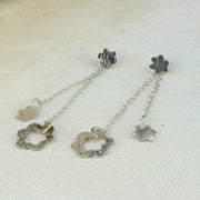 Small silver flower stdus with a striped hammered texture and a darker oxidised finish. A drop part is attached by looping the stud through a jump ring. The drop features a smaller flower and a larger open flower. Both are attached to trace chain with the larger flower a bit lower than the smaller one. Two looks in one.