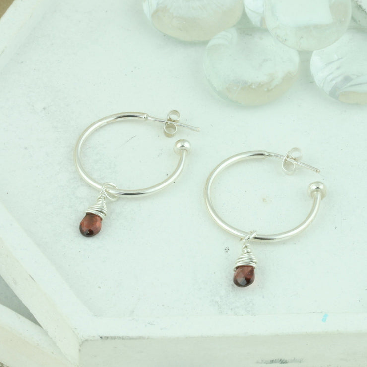 Silver hoop earrings with briolette gemstones. Classic hoop earrings, featuring a shiny polished finish. Featured here with Garnet briolette gemstones.