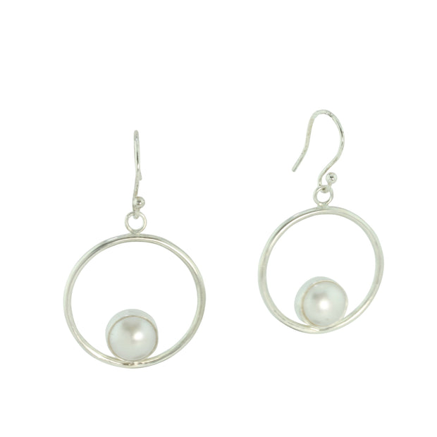 Silver hoop hook earrings featuring a freshwater pearl. The pearl is 8mm in diameter and is set in a cabochon setting at the bottom on the inside of the hoop. These are handmade earrings, made form eco-silver.