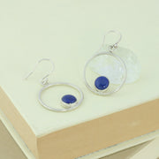 Silver hoop hook earrings featuring a Lapis Lazul gemstone. The gemstone is 8mm in diameter and is set in a cabochon setting at the bottom on the inside of the hoop. These are handmade earrings, made form ec