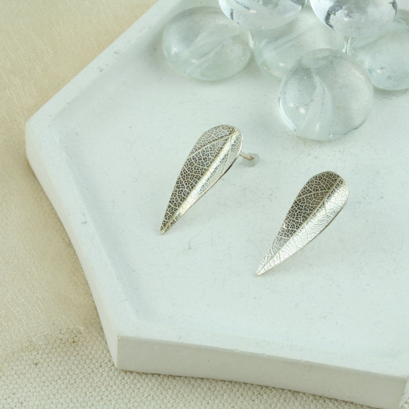 Eco silver leaf stud earrings. The leaves have a slight bend in the middle and have a real leaf texture. The texture adds sparkle to the leaf as it captures the light.