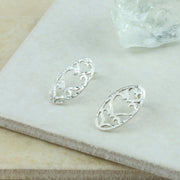 Silver oval stud earrings, about 2.3 c 1.5cm in size. Three hearts are cut out of the oval shape. The middle hearts is the lragets, and the hearts at the bottom and top are of a smaller size.