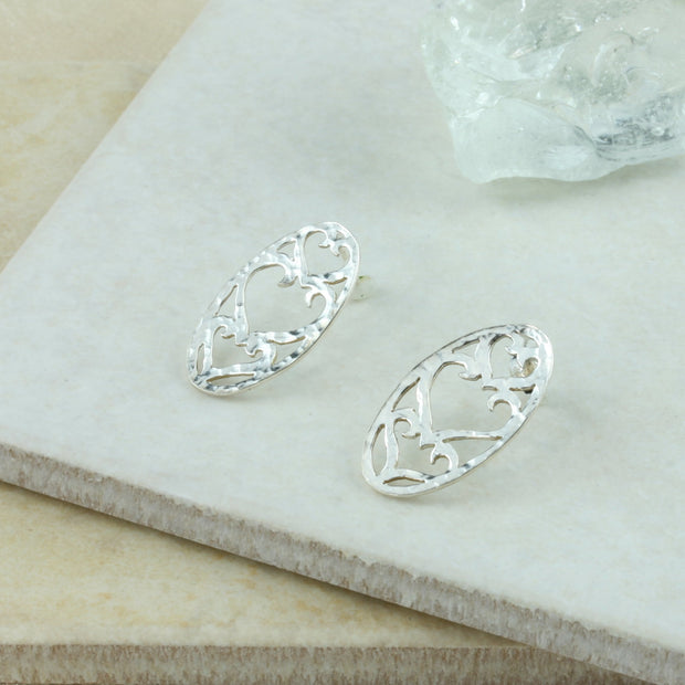 Silver oval stud earrings, about 2.3 c 1.5cm in size. Three hearts are cut out of the oval shape. The middle hearts is the lragets, and the hearts at the bottom and top are of a smaller size.