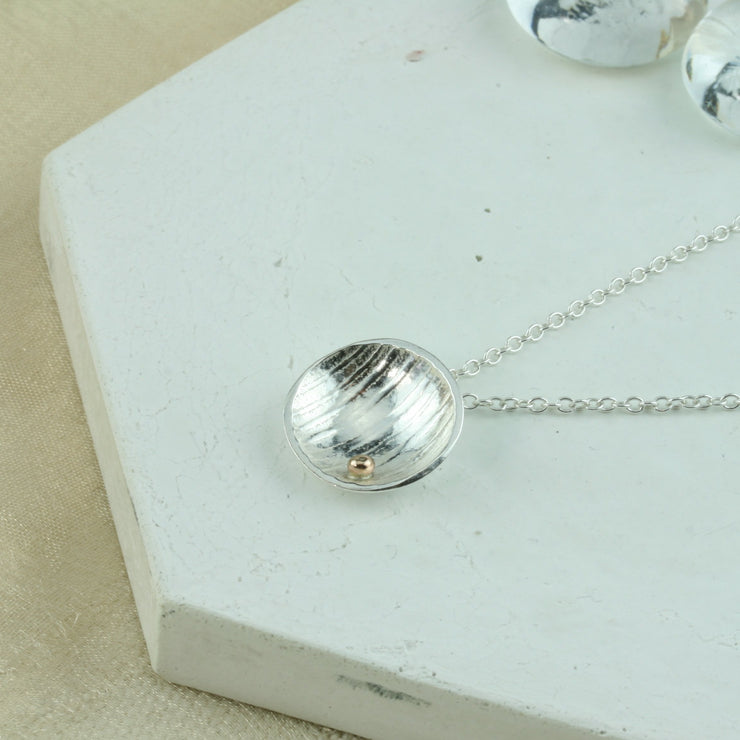 Eco silver pendant necklace with a stripe texture and mirror finish. Featuring a gold ball on the inside at the bottom half of the cup.