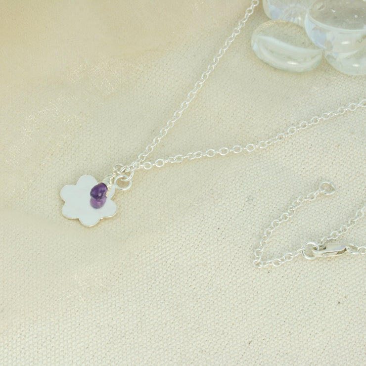Silver personalised pendant necklace with a flower shaped pendant that can be personalised with a word, name, initials or symbols of your choosing. The pendant can be fastened at various lengths. The pendant is made using eco silver. This version shows the pendant necklace with the addition of an Amethyst gemstone, more gemstones are available too.