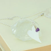 Silver personalised pendant necklace with a large heart shaped pendant that can be personalised with a word, name, initials or symbols of your choosing. The pendant can be fastened at various lengths. The pendant is made using eco silver. This version shows the pendant necklace with the addition of an Amethyst gemstone, more gemstones are available too.