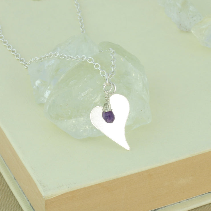 Silver personalised pendant necklace with a small heart shaped pendant that can be personalised with a word, name, initials or symbols of your choosing. The pendant can be fastened at various lengths. The pendant is made using eco silver. This version shows the pendant necklace with the addition of an Amethyst gemstone, more gemstones are available too.