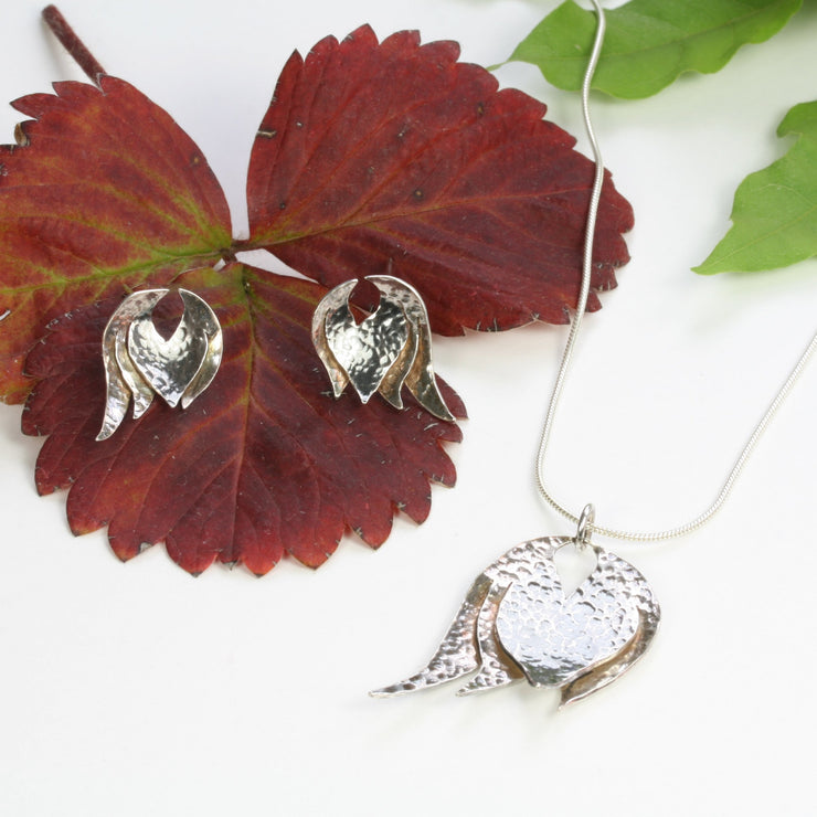 Silver pendant necklace featuring a petal pendant that has been slightly domed and textured. The heart of the petal has a darker oxidised finish. The pendant has a shiny finish and is featured by a snake chain with a lobster clasp fastening.