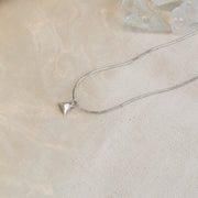 A silver pendant in the shape of a pyramid. IT has a mirror finish and comes with a snake chain necklace.