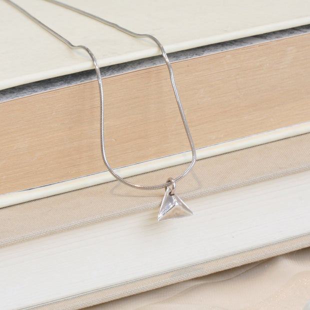 A silver pendant in the shape of a pyramid. IT has a mirror finish and comes with a snake chain necklace.