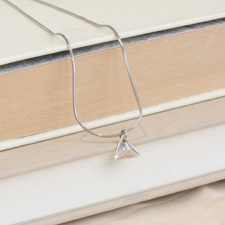 A silver pendant in the shape of a pyramid. IT has a mirror finish and comes with a snake chain necklace.