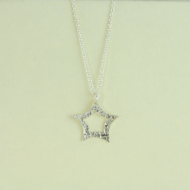 A silver necklace adjustable to two lengths featuring a star pendant. The star is open in the middle and it&