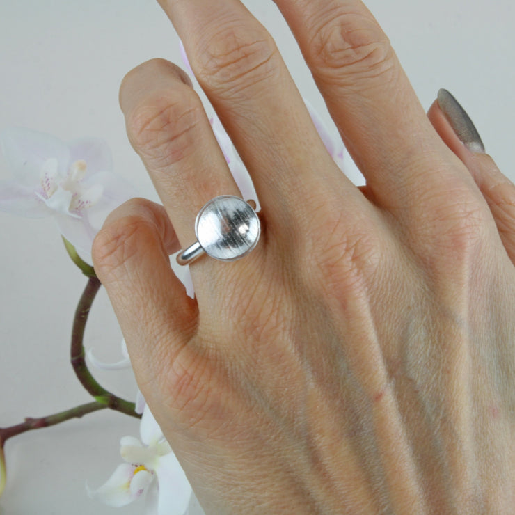 Eco silver cup ring with a silver ring band and a domed cup with a stripe texture. 