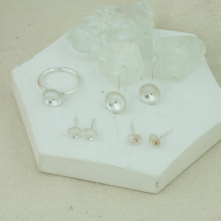 Eco silver cup ring with a silver ring band and a domed cup with a pebble texture. With stud earrings and hook earrings from the cup collection.