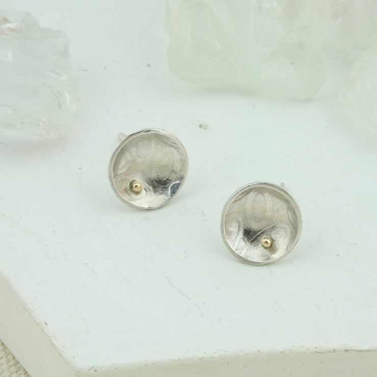 Eco silver domed cups with a pebble texture.  A 9ct gold ball sits a bit to the side at the bottom half of the cup. The earrings have a shiny finish.