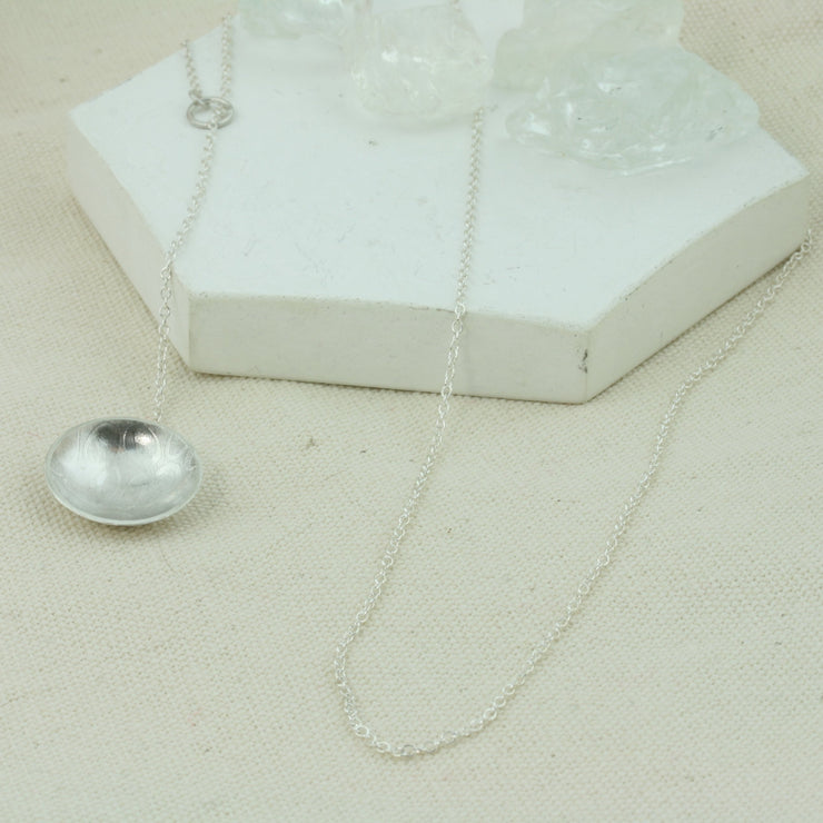Eco silver cup y necklace. A domed and texture cup is attached at the end of the chain. The chain feeds through a jump ring attached to the other end of the chain, so it slides through and can be adjustable in length.