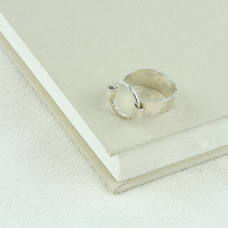 Silver hoop ring with a 9mm wide ring band and a loop held in place by both ends of the band. It has a hammered shiny finish for added sparkle.