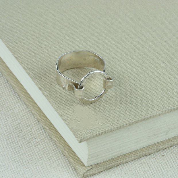 Silver hoop ring with a 9mm wide ring band and a loop held in place by both ends of the band. It has a hammered shiny finish for added sparkle.