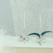 Silver earrings featuring a snowflake with a hammered shiny finish, which sparkles in the light. The snowflake is attached to the silver wire that loops through the ear and drops 5cm on both sides, showing off the snowflake perfectly.