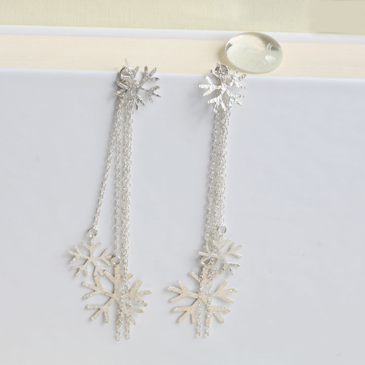 Silver snowflake earrings featuring a stud earring which can be worn on its own. The drop part can be added by looping the stud through the jump ring which features four chains, of which two have a snowflake attached at the bottom. One is larger than the other. The total length of the drop is 10cm / 4". Seen here in combination with the silver snowflake pendant necklace.