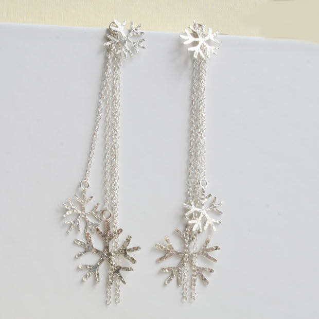 Silver snowflake earrings featuring a stud earring which can be worn on its own. The drop part can be added by looping the stud through the jump ring which features four chains, of which two have a snowflake attached at the bottom. One is larger than the other. The total length of the drop is 10cm / 4". 