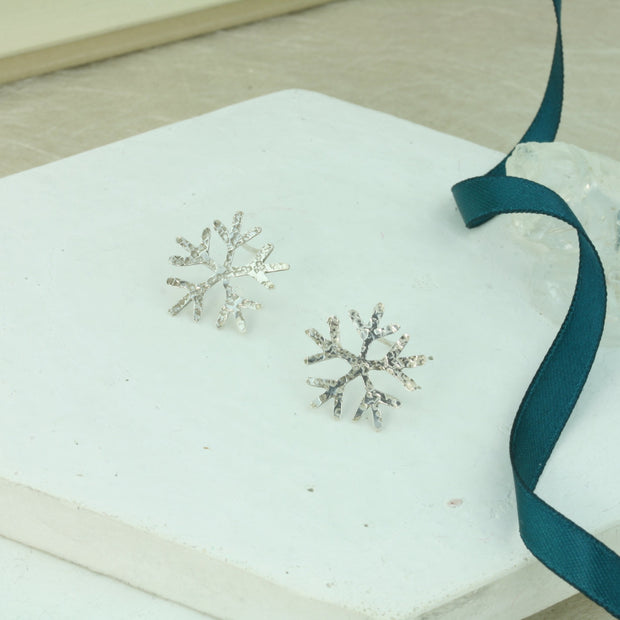 Snowflake stud earrings featuring a hammered texture with a shiny finish. these are hand sawn so every pair may be slightly different.