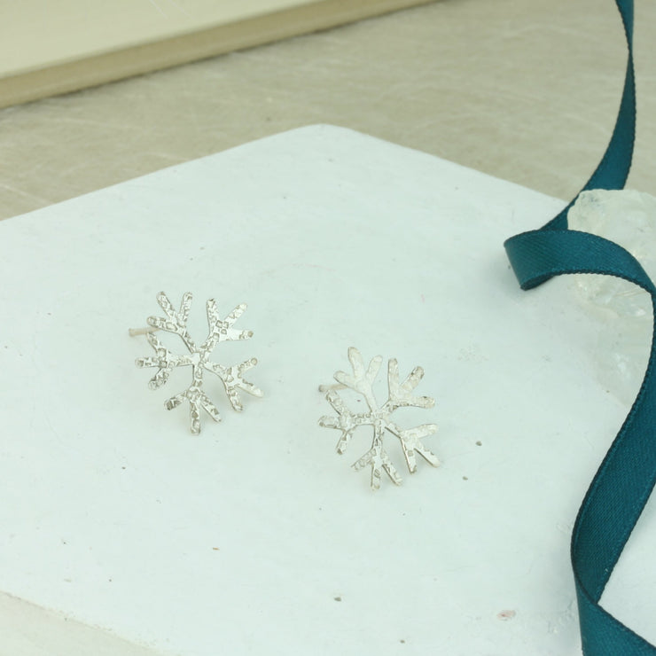 Snowflake stud earrings featuring a hammered texture with a shiny finish. these are hand sawn so every pair may be slightly different.