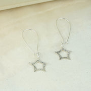 Eco silver long wired earring hooks with a star dangling from the bottom. The front has a hammered shiny finish that sparkles in the light. The back has a mirror finish.