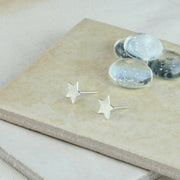 Eco silver stud earrings in the shape of a five pointed star. They have a round hammered shiny finish.