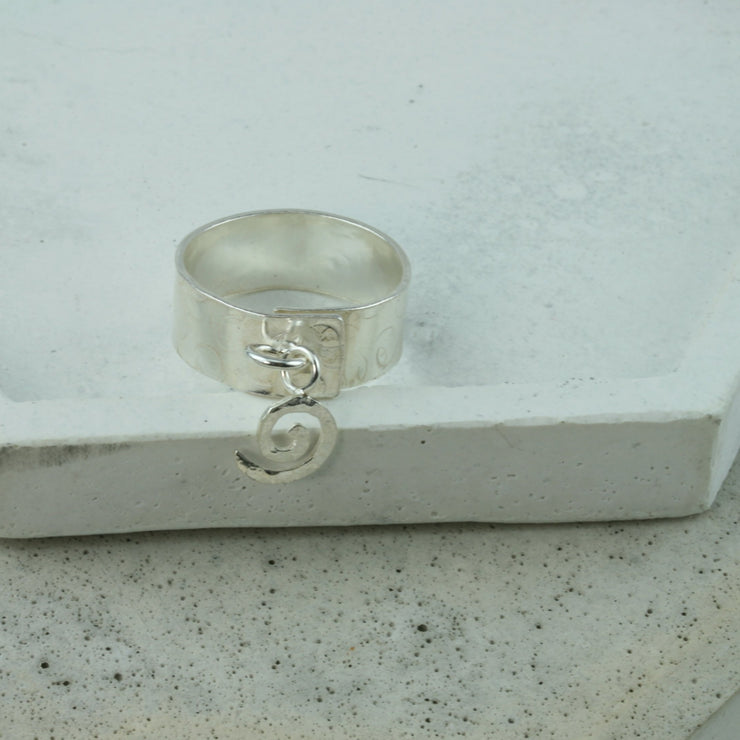 Silver ring band 7mm wide and with a round hammered finish. This ring is adjustable meaning it wraps around the finger and isn&