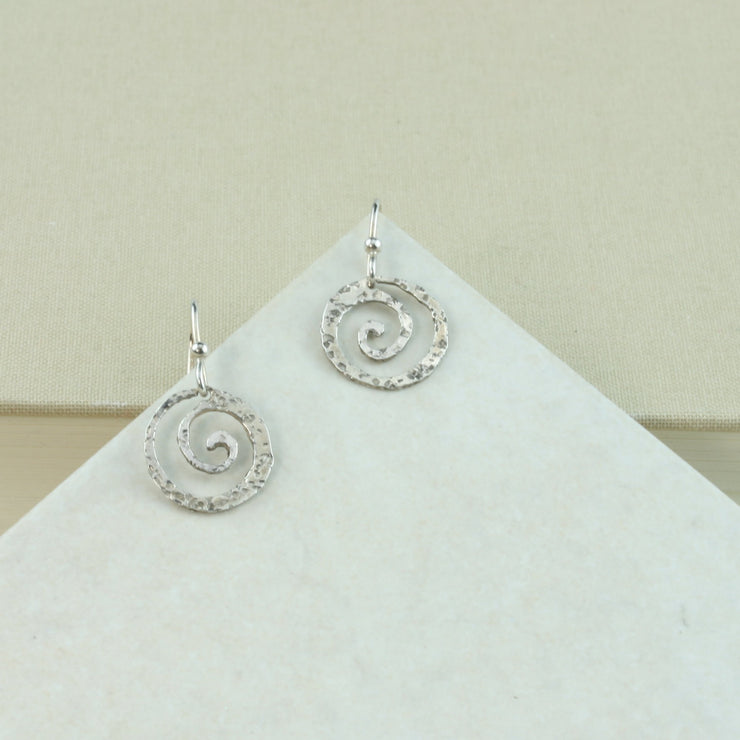 Silver hook earrings featuring a round swirl shape with a hammered texture.