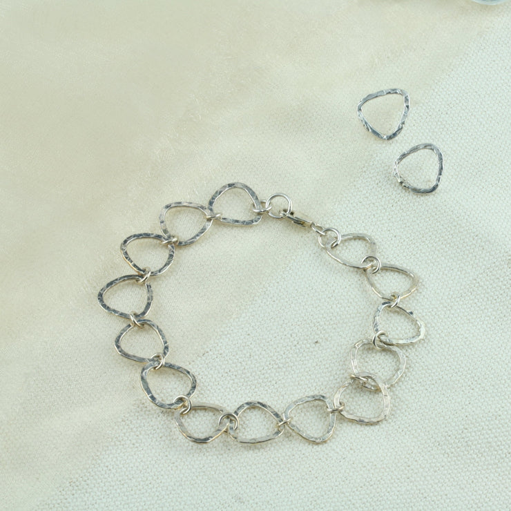 Silver triangle bracelet, featuring triangle shaped links attached to each other with round jump rings. The triangles have a hammered finish to give the triangles a shimmery look. It&