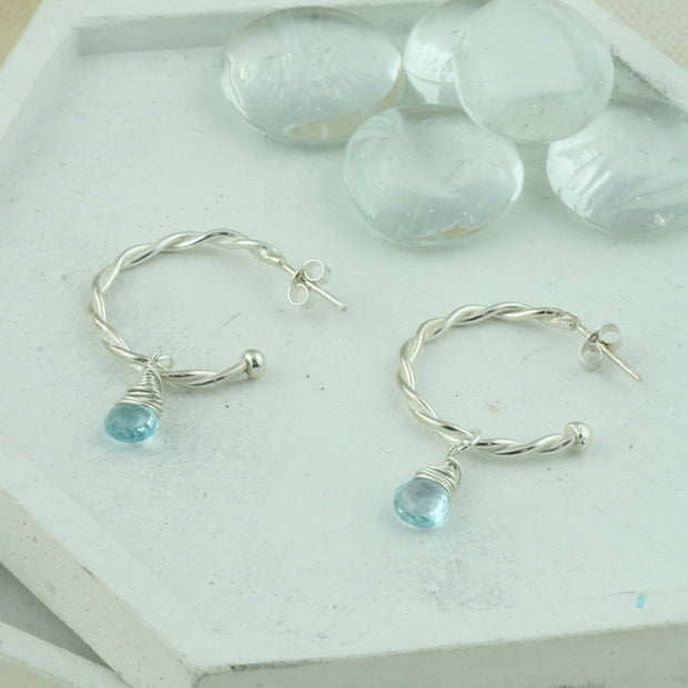 Silver hoop earrings with briolette gemstones. Hoop earrings made with two twisted silver wires, featuring a shiny polished finish. Featured here with London Blue Topaz briolette gemstones.