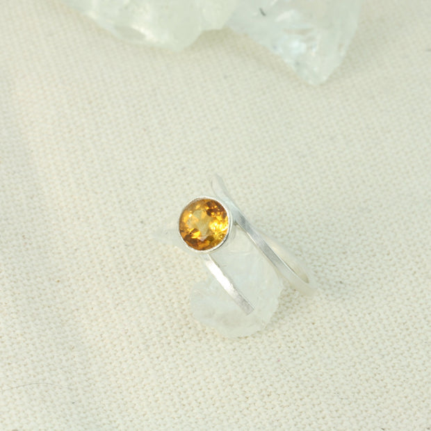 Silver twisted ring made from square eco silver wire. In between the two sides sits a Citrine gemstone in a collet setting. The collet setting raises the gemstone about 10mm above the ring band. The band is adjustable to a few sizes up or down.