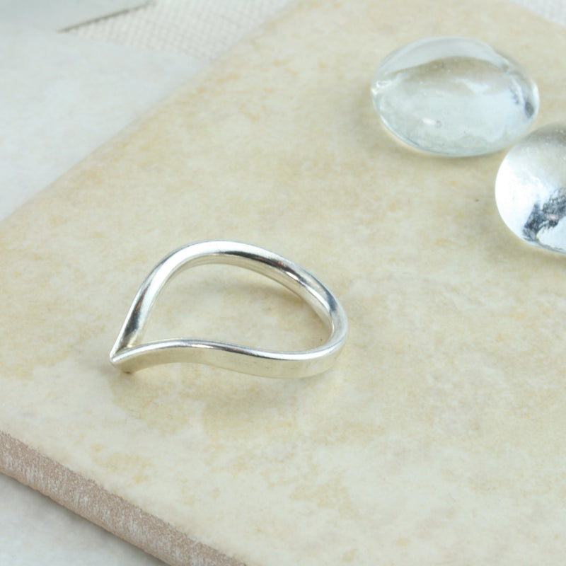 Eco silver wishbone ring. This ring is made using D shaped wire with the curve on the inside and the flat side on the outside. The rich dips into a V-shape on one side. This design is beautiful on its own and in combination with a gemstone ring allowing space to wrap around it.
