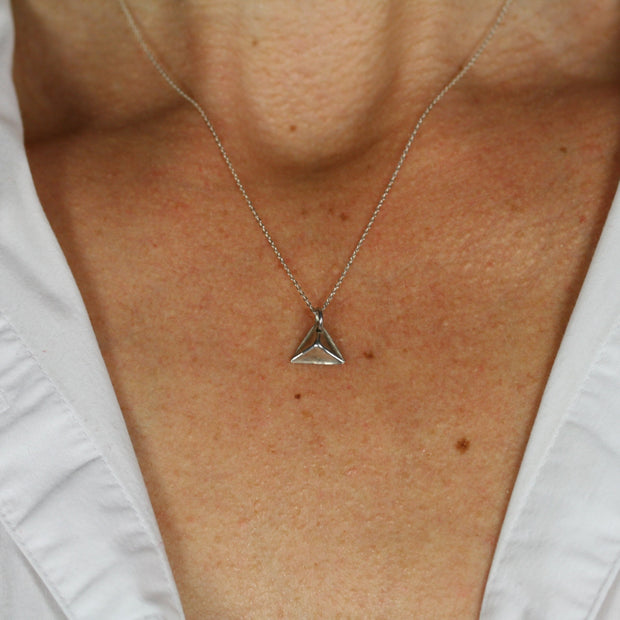 A silver pendant in the shape of a pyramid. IT has a mirror finish and comes with a snake chain necklace.