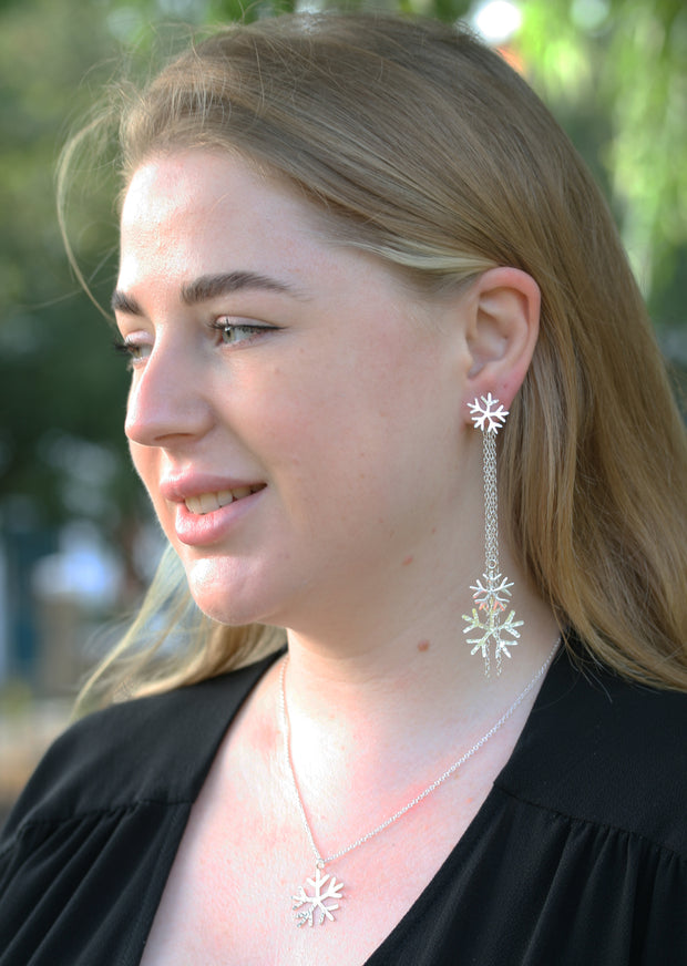 Silver snowflake earrings featuring a stud earring which can be worn on its own. The drop part can be added by looping the stud through the jump ring which features four chains, of which two have a snowflake attached at the bottom. One is larger than the other. The total length of the drop is 10cm / 4". Seen here in combination with the silver snowflake pendant necklace.