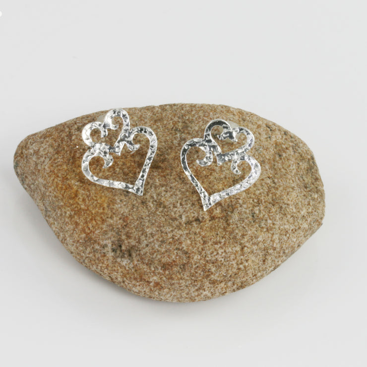 Eco silver heart stud earrings. They have a hammered texture and shiny polished finish.
