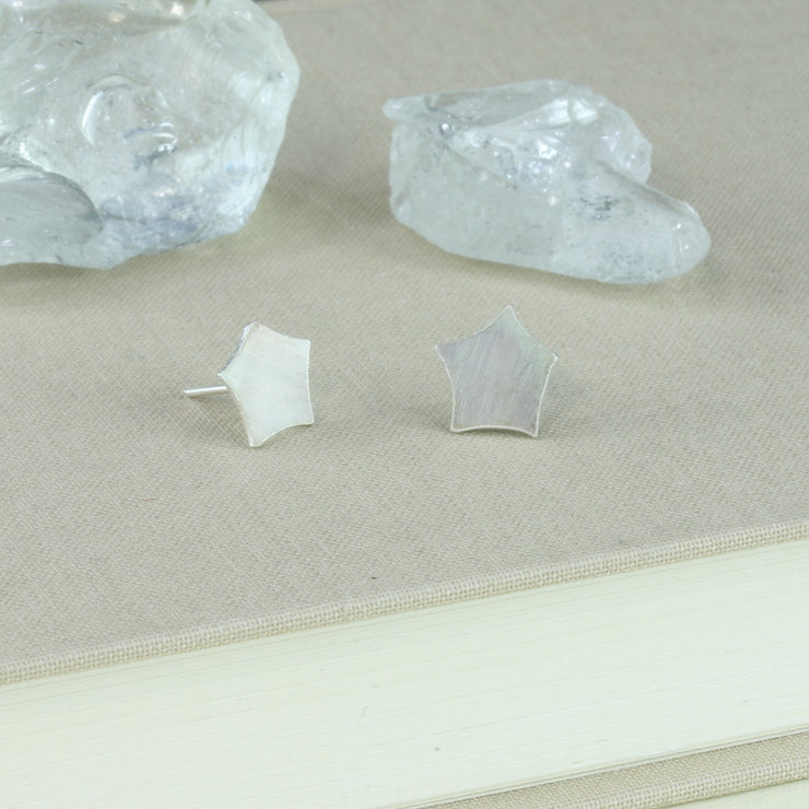 Eco silver stud earrings with a star shape with rounded off ends. They have a matte finish.
