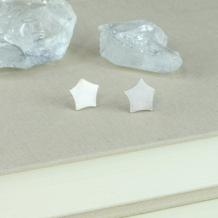 Eco silver stud earrings with a star shape with rounded off ends. They have a matte finish.